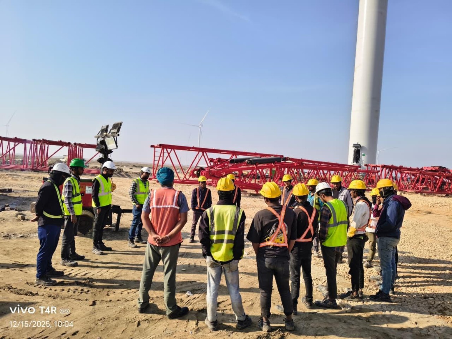 Site team briefing beside a wind turbine
