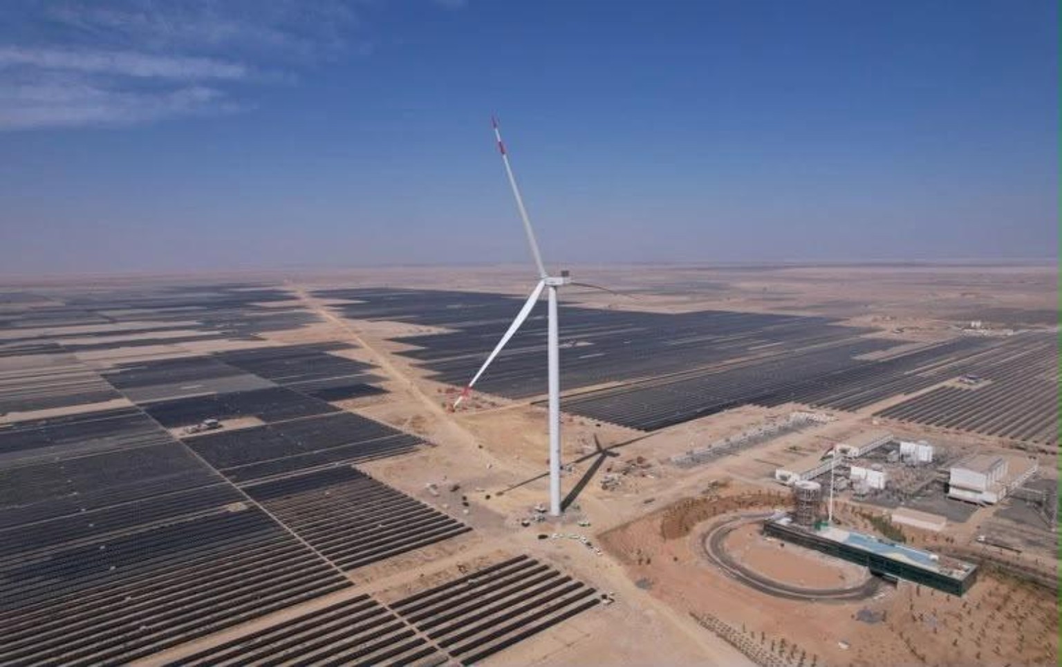 Solar arrays and a wind turbine in a renewable energy landscape